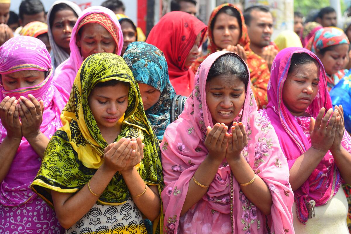 Family members of missing garment workers offer prayers in front of the rubble of a factory building that collapsed on the outskirts of Dhaka, Bangladesh.