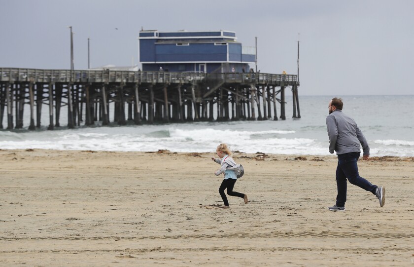 Jim Freeman and his daughter Emma are running in the cold wind just before the rain starts to fall on Wednesday at Newport Pier.