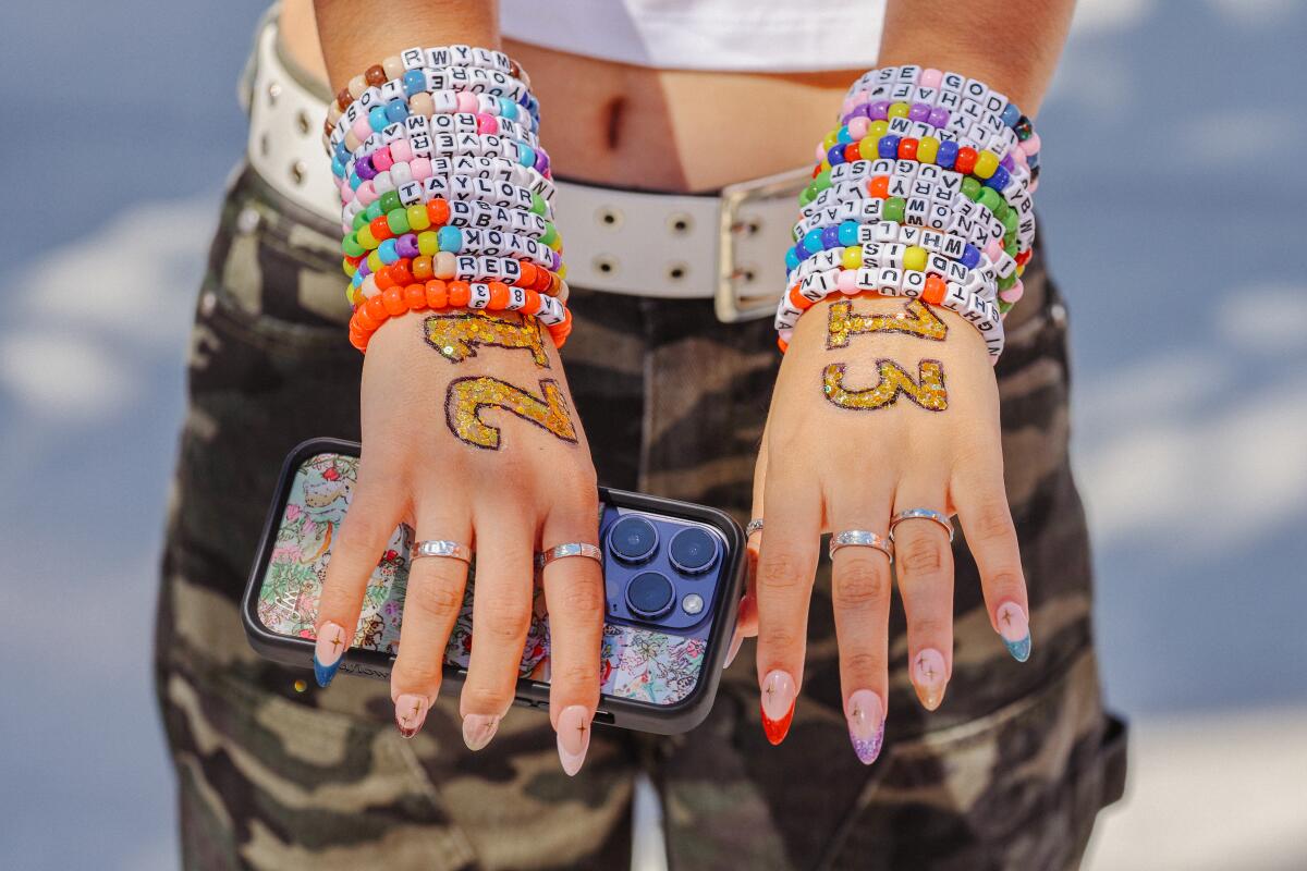 A young woman holds out her hands, her wrists covered in multicolored friendship bracelets.