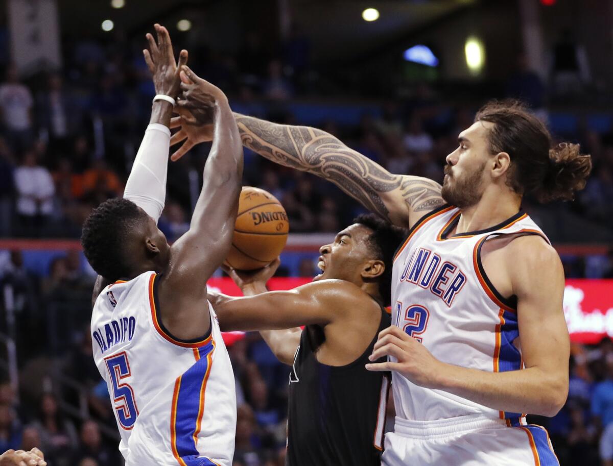 Suns forward T.J. Warren (12) is caught between Oklahoma City Thunder guard Victor Oladipo (5) and center Steven Adams (12) during the second half of a game on Oct. 28.