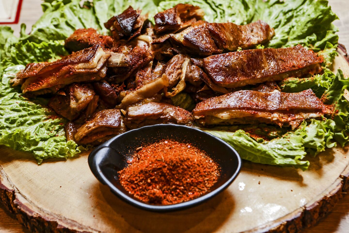 Smoked lamb chops are served with a bowl of spice mix.