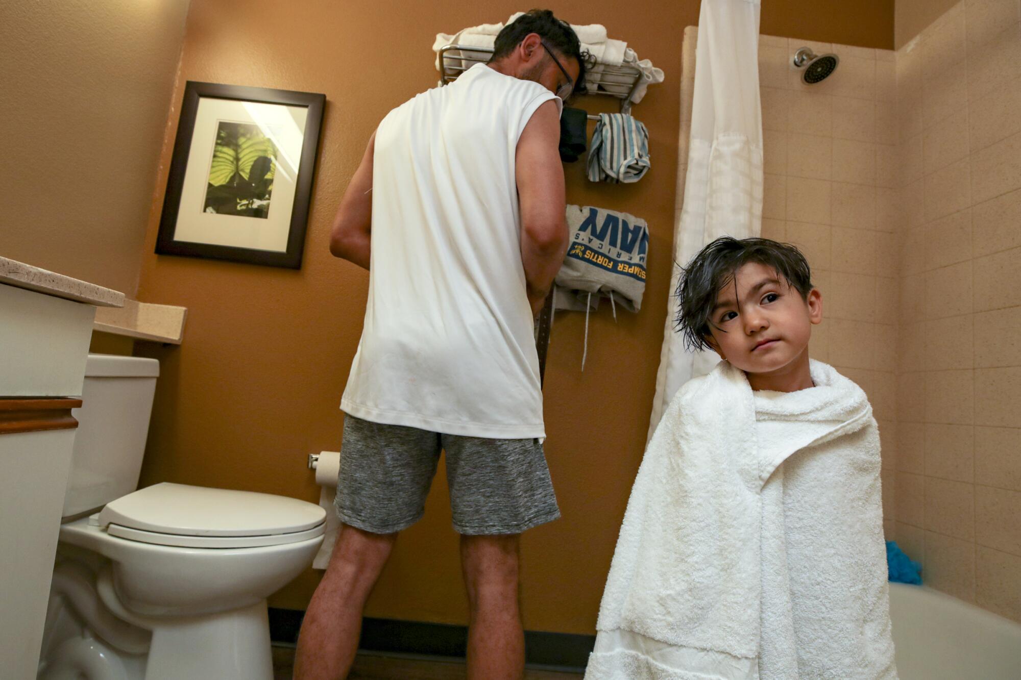 Zabih Khan bathes his 4-year-old brother Mojib at a hotel in San Diego.