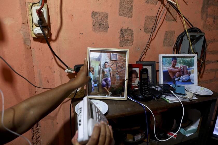 In this Oct. 10, 2019 photo, María Teresa Carballo, shows a picture of her grandson Antony inside of her house in Santa Ana, El Salvador. On a stormy night in 2010, her 17-year-old grandson, Antony, disappeared after being lured from home by a classmate who said there was a girl who wanted to meet him. The classmate was joining a gang and Antony, a resident of the rival gang’s territory, was his ticket in. Antony’s body was discovered two years later in a septic pit. (AP Photo/Eduardo Verdugo)