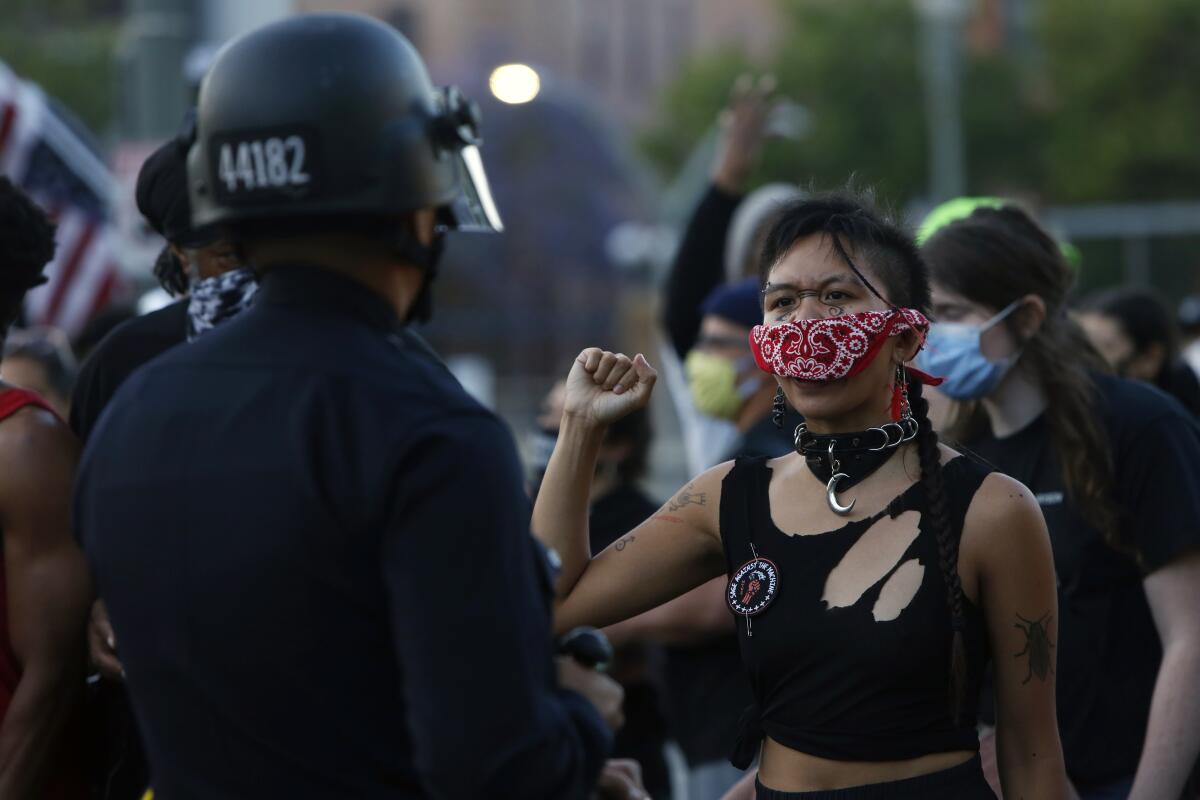 A woman makes a fist as a helmeted police offer looks on