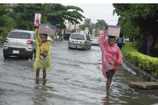 FILE - Women walk along a flooded street after a heavy downpour in Lagos, Nigeria, July 10, 2024. (AP Photos/Sunday Alamba, File)