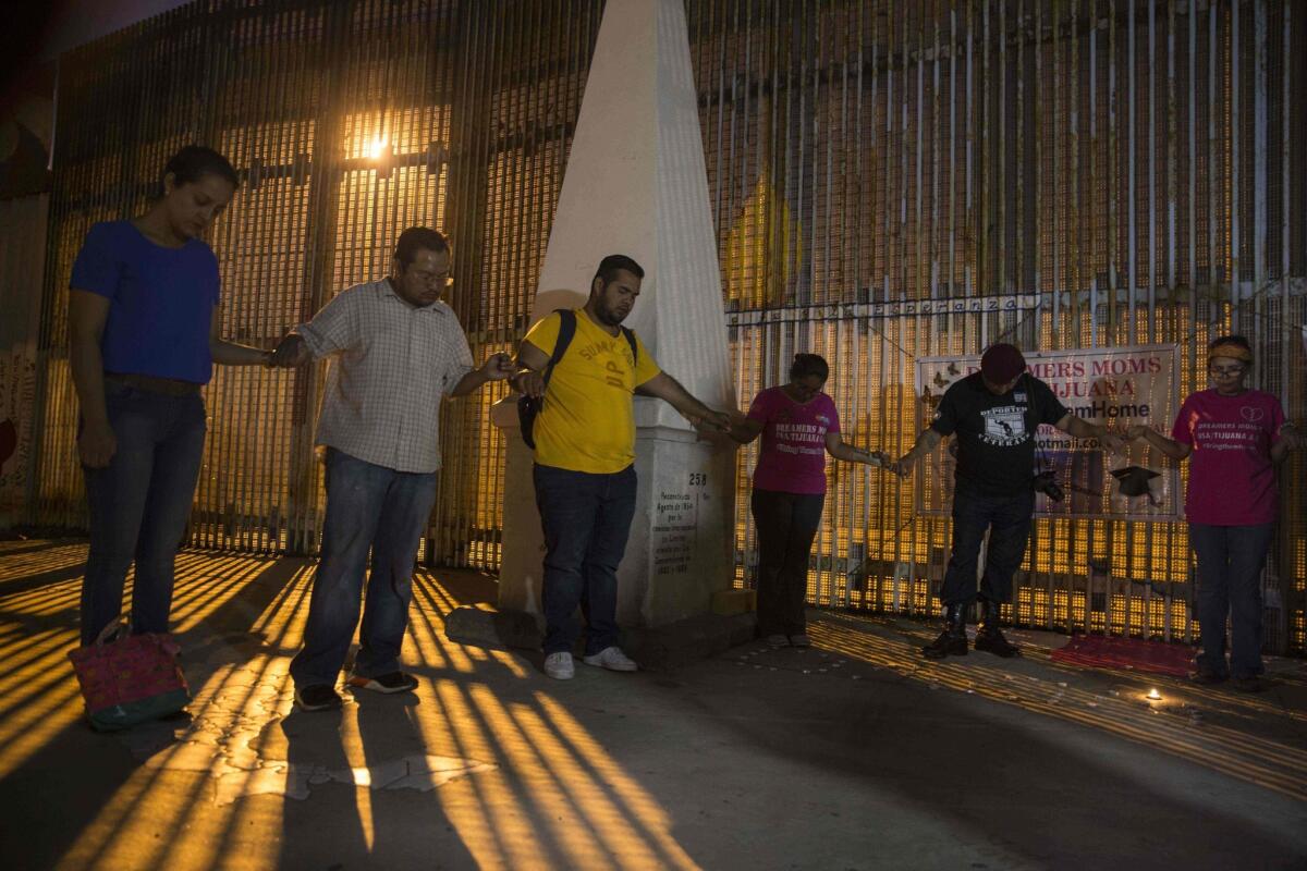 Activists pray at the wall between Mexico and the U.S. during a protest against the possibility of the deportation of Dreamers included in the DACA program.