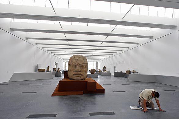 A worker puts the final touches on a vent where the "Olmec: Colossal Masterworks of Ancient Mexico" is being featured at the soon-to-open Resnick Exhibition Pavilion at the Los Angeles County Museum of Art. Colossal Head 5, center, anchors this part of the exhibition.
