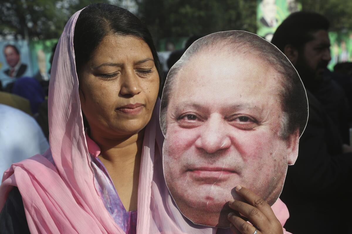 A supporter of former Pakistani Prime Minister Nawaz Sharif holds a picture of him at an airport in Lahore on Tuesday.