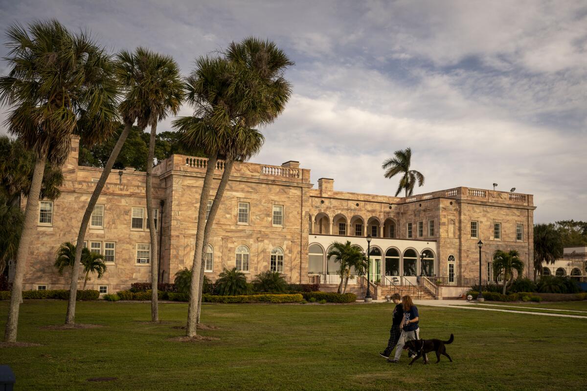 A view of a college campus with brick building and a row of palm trees