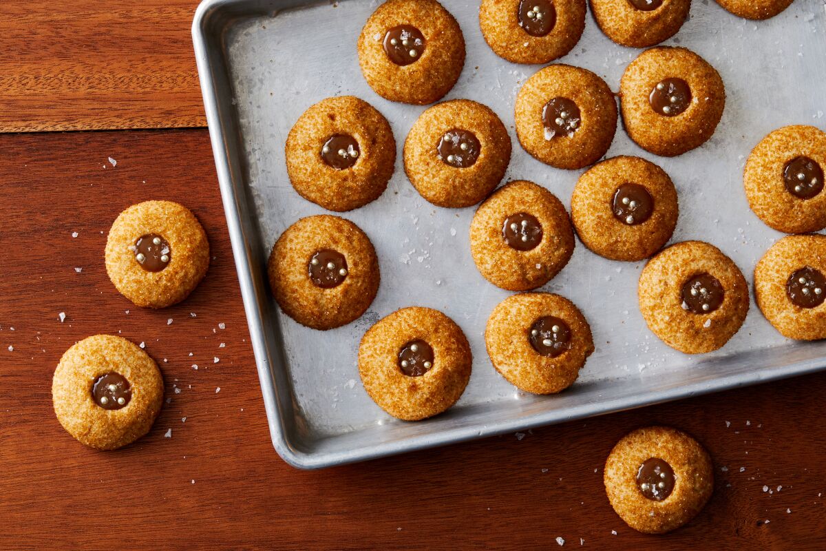 The iconic L.A. dessert salted butterscotch budino transforms into shiny gold thumbprint cookies here, filled with whiskey butterscotch sauce and dolled up with gold dragées.