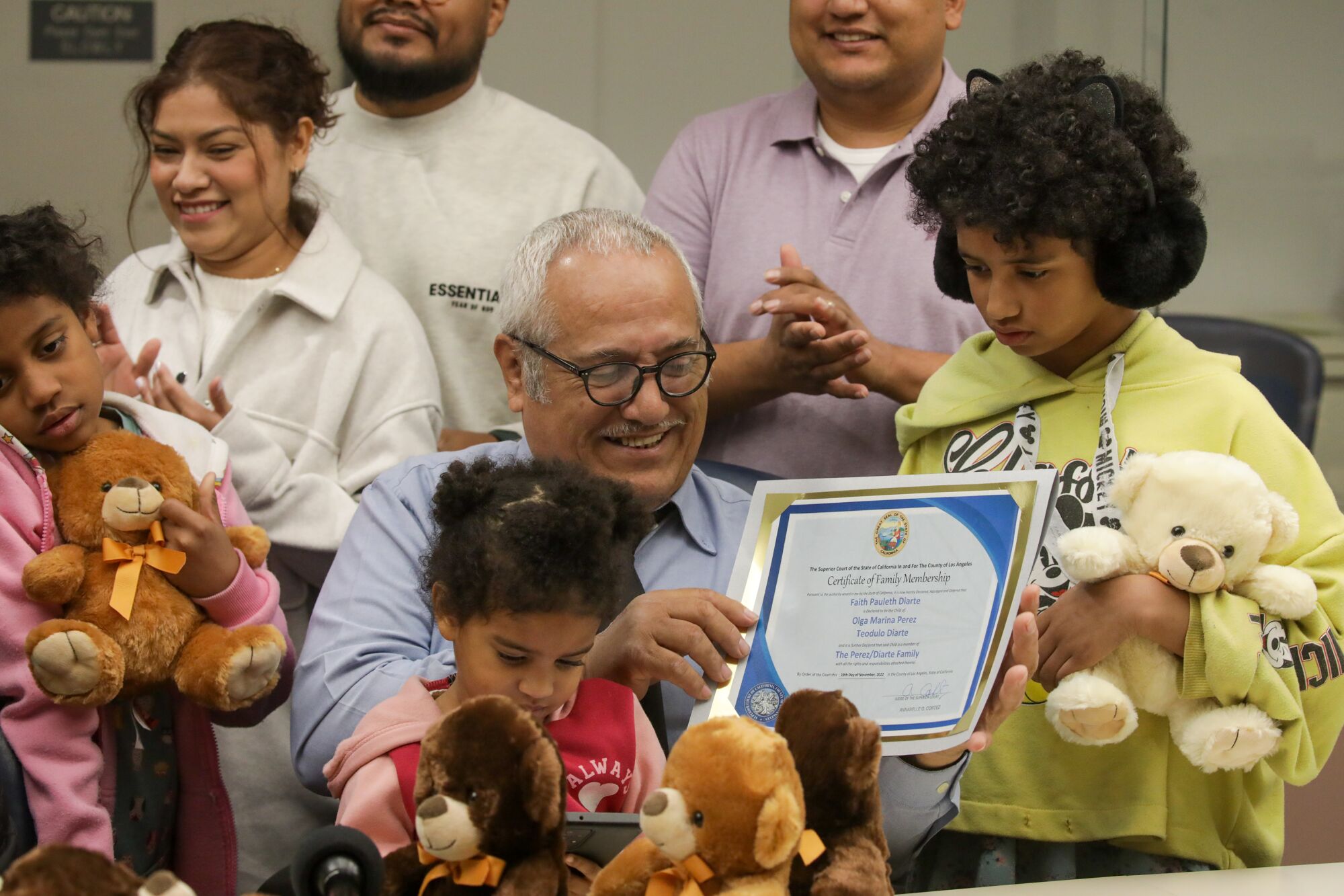 A man holds up a certificate surrounded by family and children