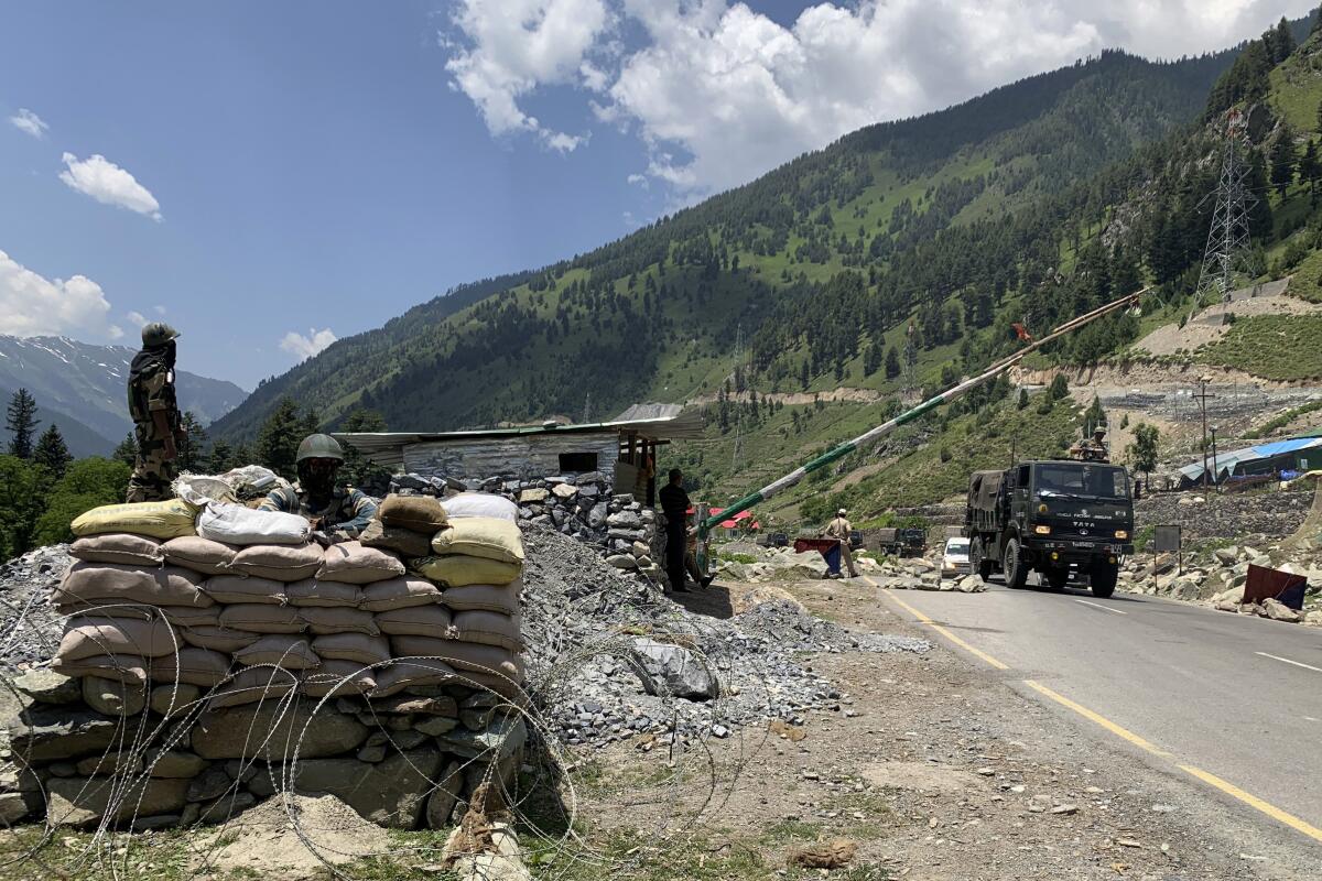 Paramilitary soldiers keep guard as an Indian army convoy moves on the Srinagar-Ladakh highway in northern India.