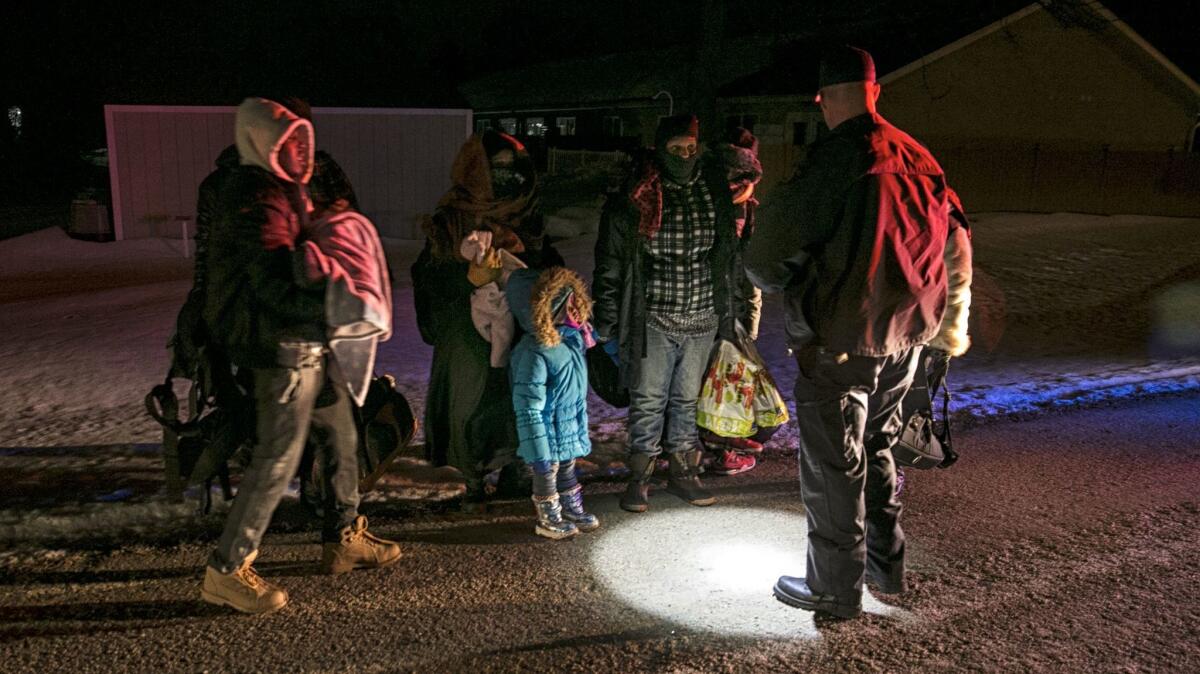 Constable Richard Graham of the Royal Canadian Mounted Police detains a group of migrants who crossed into Emerson, Canada, from the U.S. in the early hours of Feb. 19.