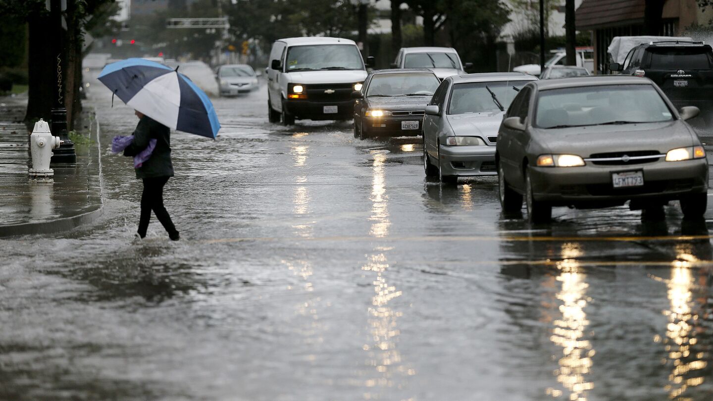 A pedestrian wades through a flooded 4th Street in Santa Ana.