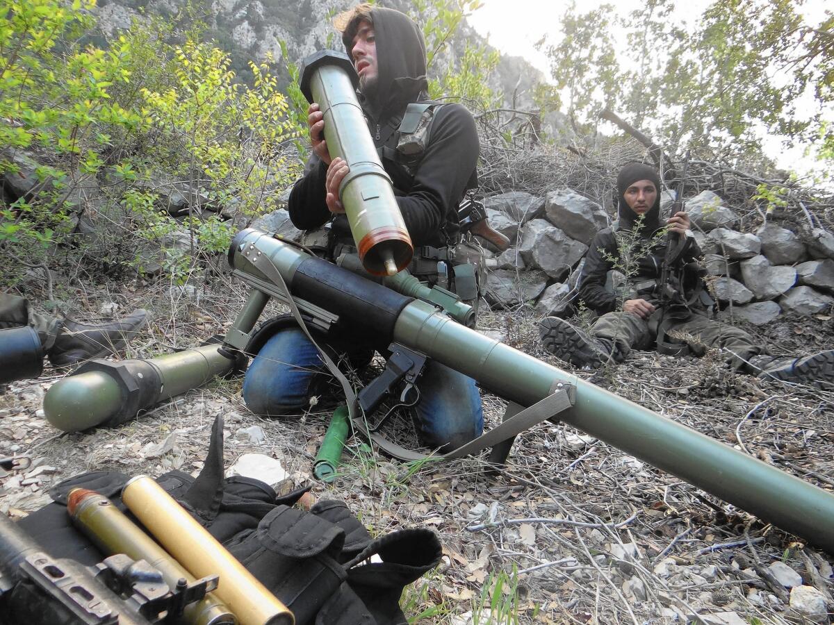 A Syrian rebel checks a launcher near the town of Kasab, in Latakia province. The United Nations says more than 1,500 families have fled.