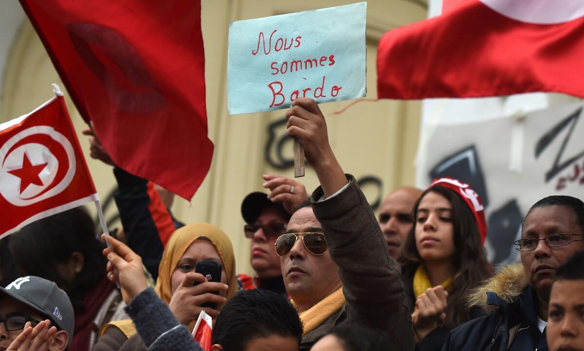 Tunisians hold placards saying "We are Bardo" and wave their national flag during a demonstration on Bourguiba Avenue in Tunis on Friday, two days after gunmen attacked the National Bardo Museum.
