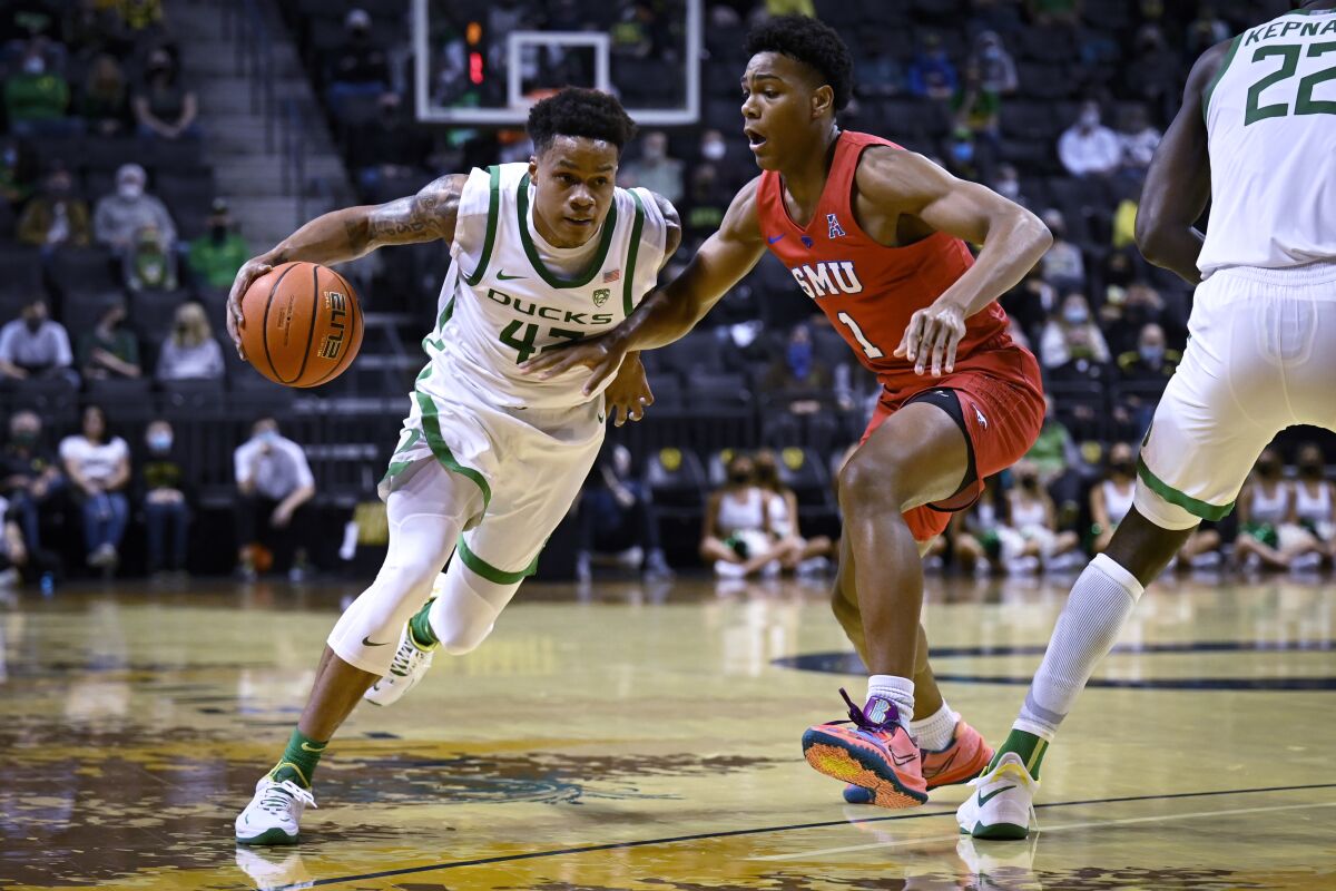 Oregon guard Jacob Young (42) drives against SMU guard Zhuric Phelps (1) during the first half of an NCAA college basketball game Friday, Nov. 12, 2021, in Eugene, Ore. (AP Photo/Andy Nelson)