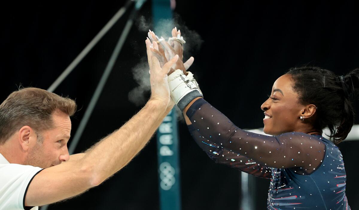 U.S. gymnast Simone Biles high-fives coach Laurent Landi.