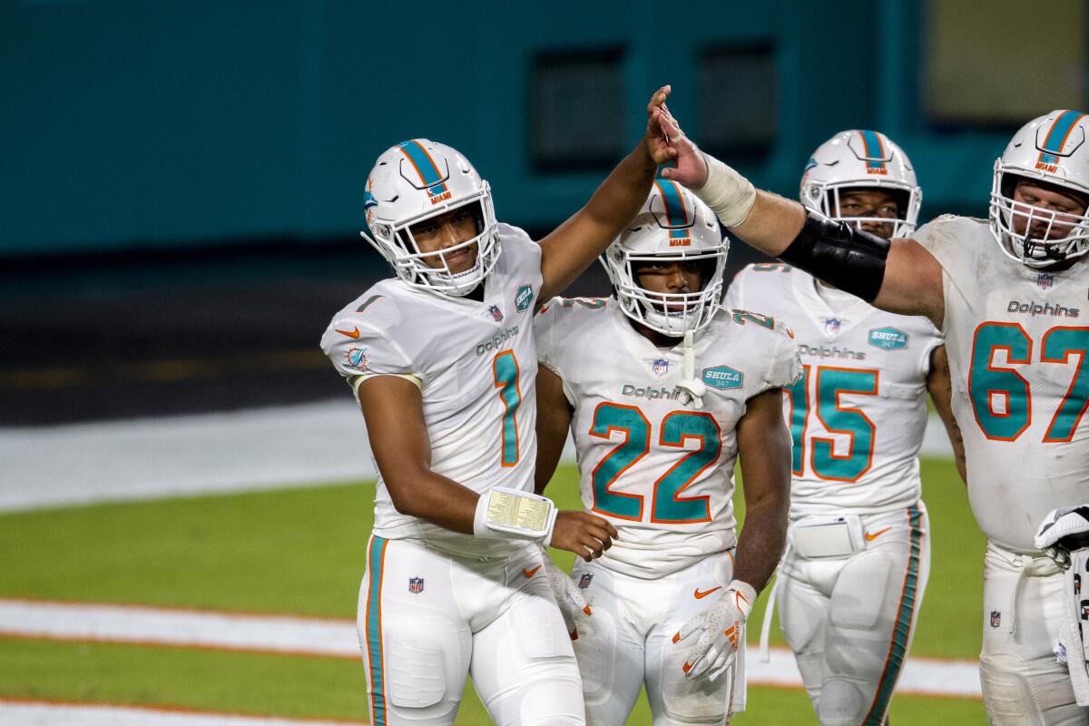 Miami Dolphins quarterback Tua Tagovailoa (1) celebrates his first NFL play with teammates.