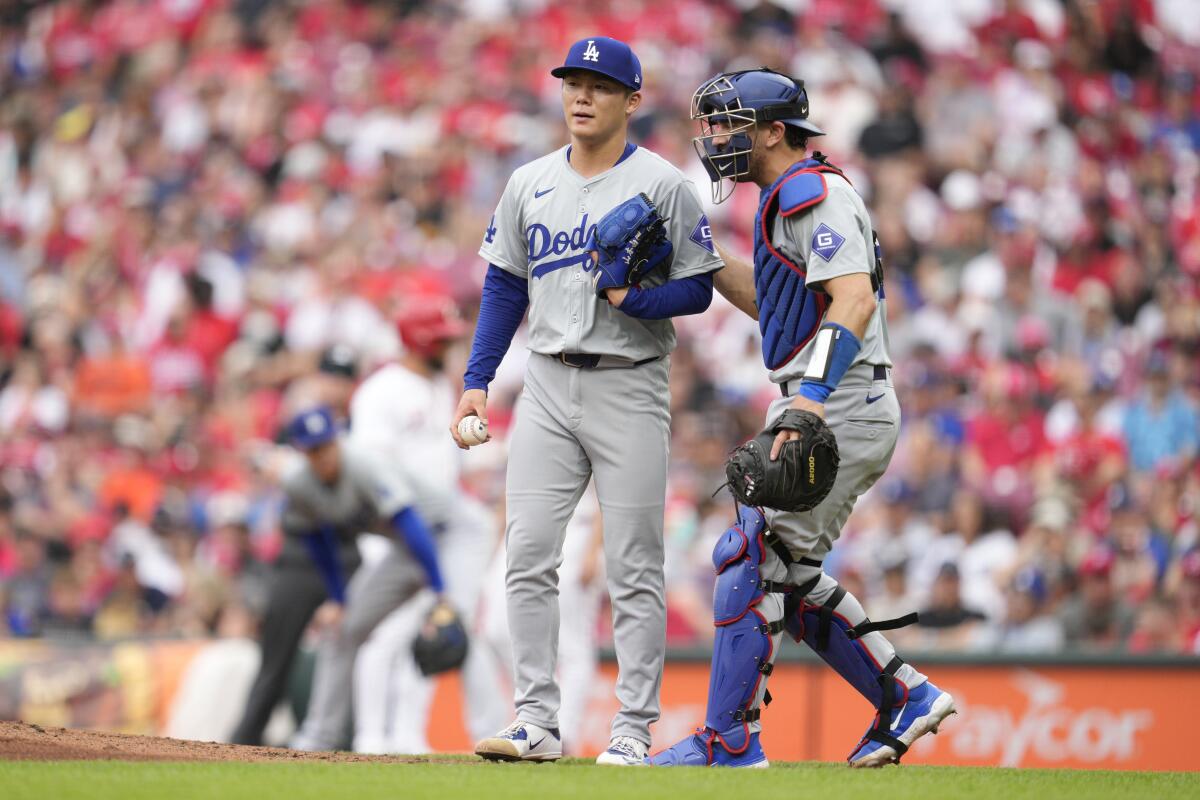 Dodgers catcher Austin Barnes taps pitcher Yoshinobu Yamamoto on the back and speaks with him during a game.