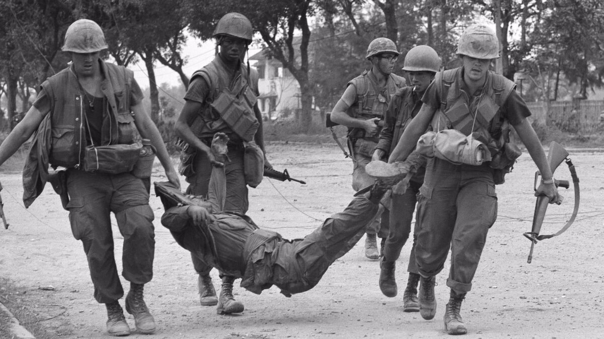 U.S. Marines drag casualty from street in Hue, Vietnam, Feb. 4, 1968.