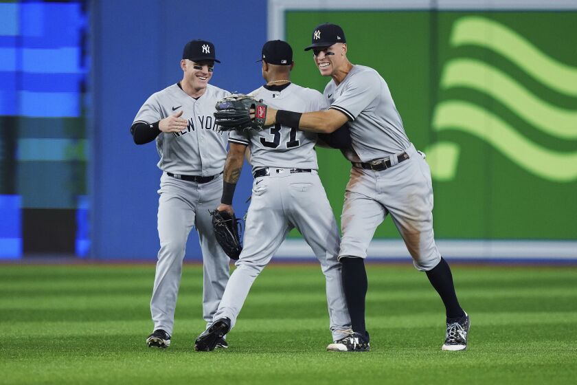 New York Yankees' Harrison Bader, Aaron Hicks and Aaron Judge, from left, celebrate the team's 5-2 win over the Toronto Blue Jays in a baseball game Tuesday, Sept. 27, 2022, in Toronto. (Nathan Denette/The Canadian Press via AP)