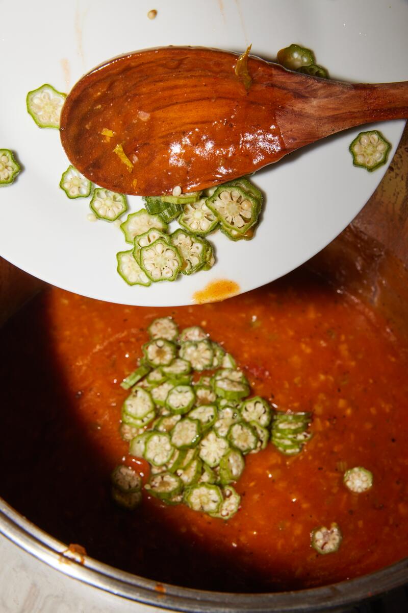 Sliced okra is added into a pot of simmering gumbo.