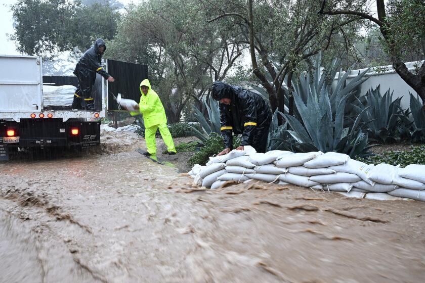MONTECITO CA JANUARY 9, 2023 - Workers stack Sandbags in front of residence on Olive Mill Road in Montecito on Monday, January 9, 2023. (Michael Owen Baker/For The Times)