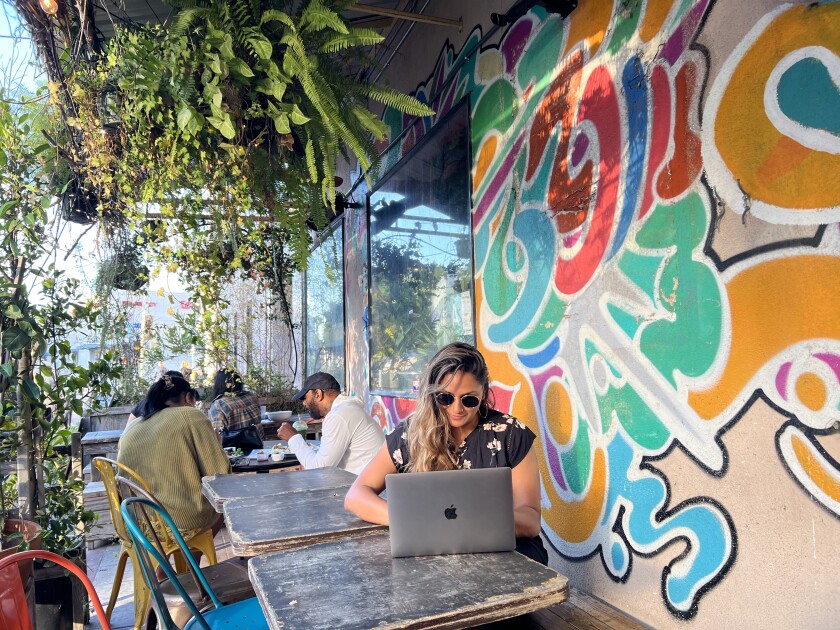 A woman works on a laptop on the patio at Yuko's Kitchen. 