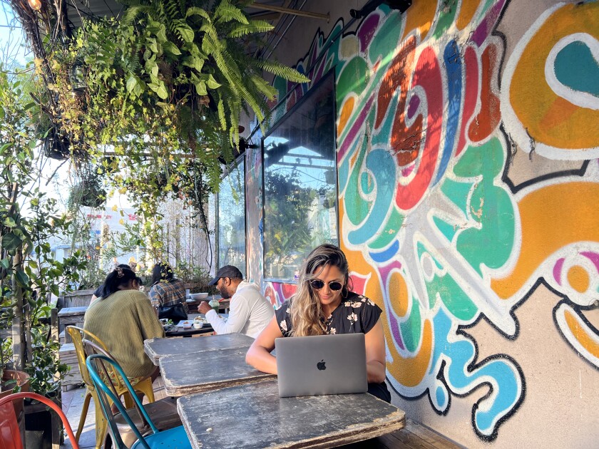 A woman works on a laptop on the patio at Yuko's Kitchen.