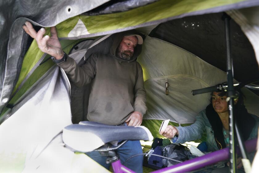San Diego, CA - January 03: On Wednesday, Jan. 3, 2024, in downtown San Diego, CA, Sean Wagner, 56, and Sabrina, in their tent currently setup on the walkway on the corner of Park Blvd. and E Street, did their best to stay warm and dry during the downpours on Wednesday, Jan. 3, 2024. Wagner says he has signed up for the safe sleeping site and is on the wait list. (Nelvin C. Cepeda / The San Diego Union-Tribune)