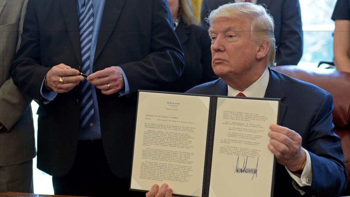 President Trump shows off the executive memorandum on an investigation of steel imports after signing it.