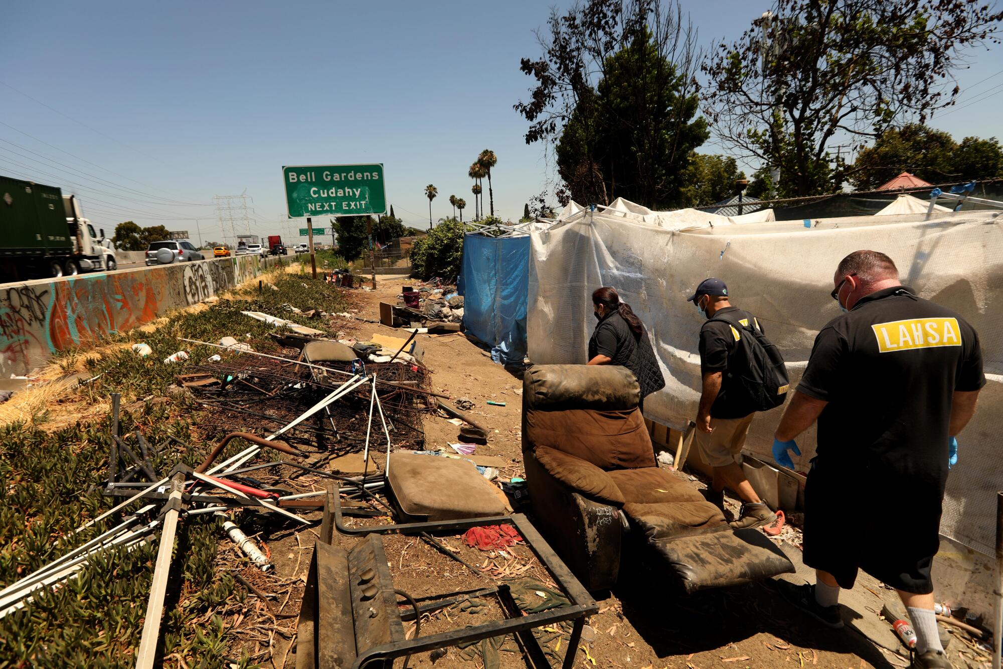 From right, John Oliver,  Jimmy Vasquez, Kim Barnett check on homeless encampments along the 710 in Bell Gardens.