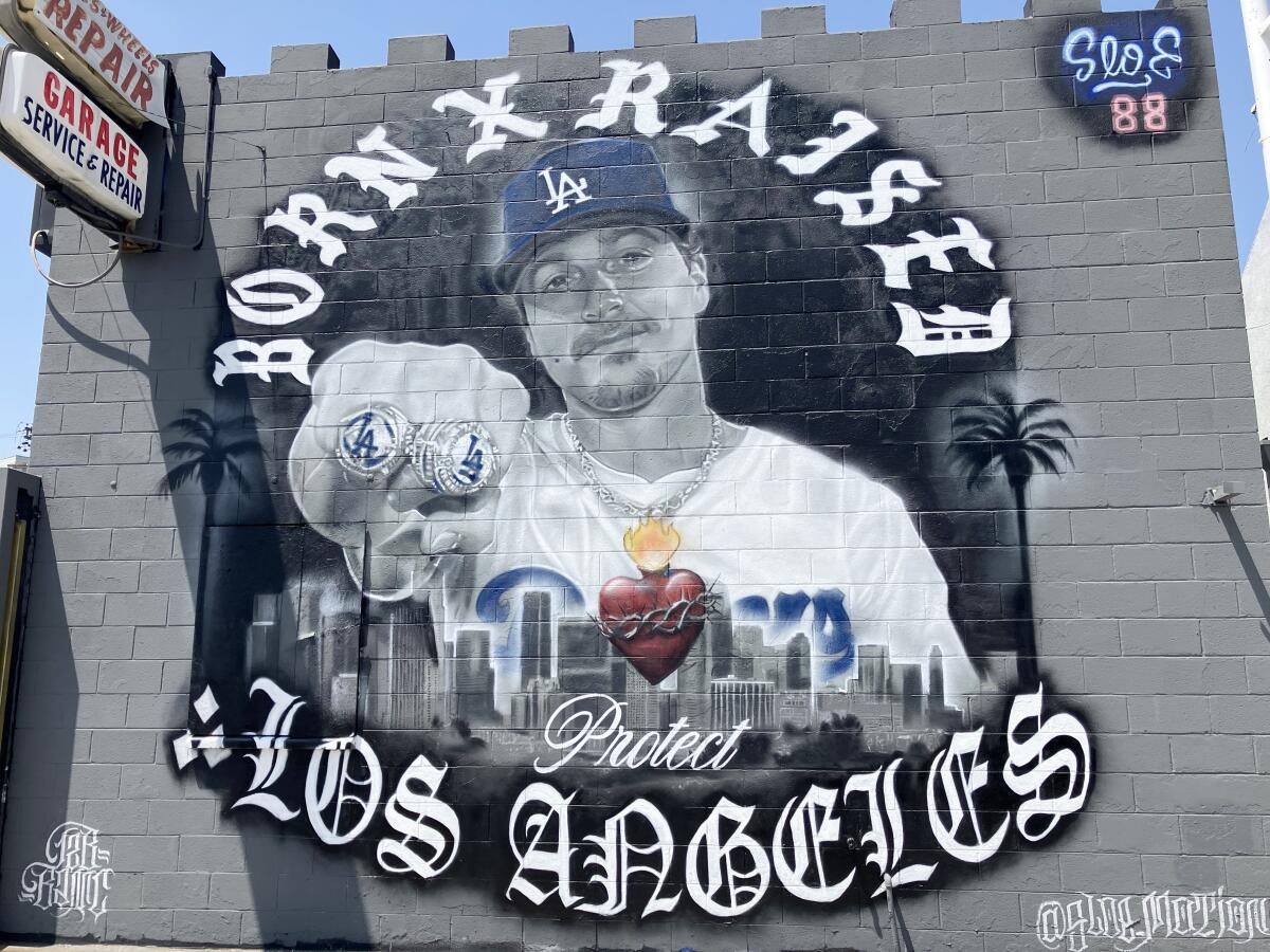 A mural on a gray exterior wall features a portrait of Kiké Hernández showing his right hand with two championship rings