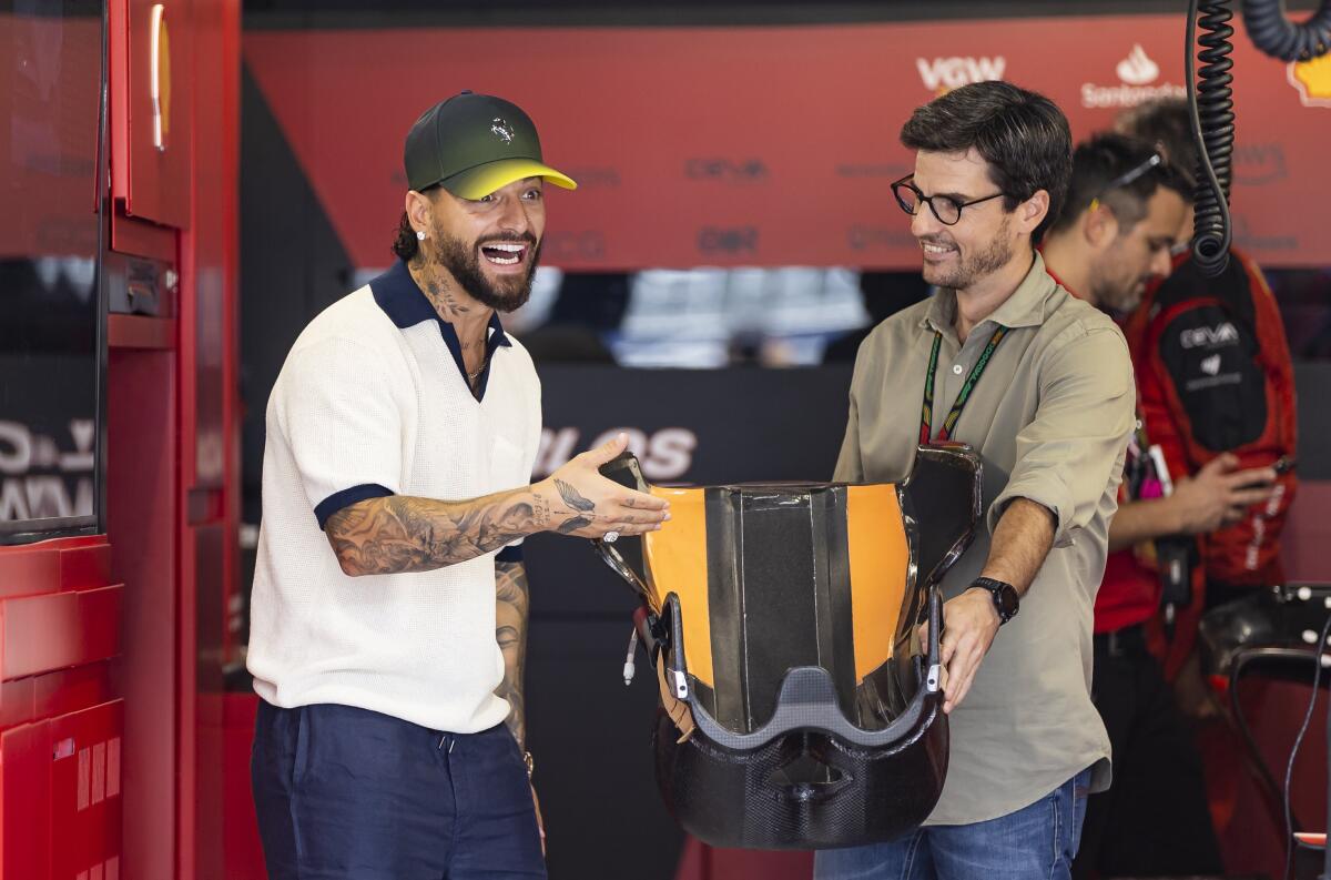El cantante colombiano Maluma, izquierda, y Carlos Oñoro Sainz visitan el garage de Ferrari