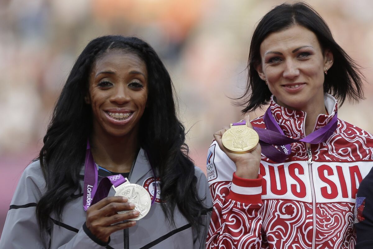 FILE - Russia's Natalya Antyukh holds the gold medal, United States' Lashinda Demus, left, the silver medal a during a ceremony for the women's 400-meter hurdles in the Olympic Stadium at the 2012 Summer Olympics, London, on Aug. 9, 2012. American runner Lashinda Demus has officially become an Olympic champion at the age of 40 and more than a decade after the 2012 London Games. The International Olympic Committee has formally reallocated Demus the gold medal in the 400-meter hurdles. The original winner was Natalya Antyukh of Russia who was later implicated in doping. (AP Photo/Matt Slocum, FIle)