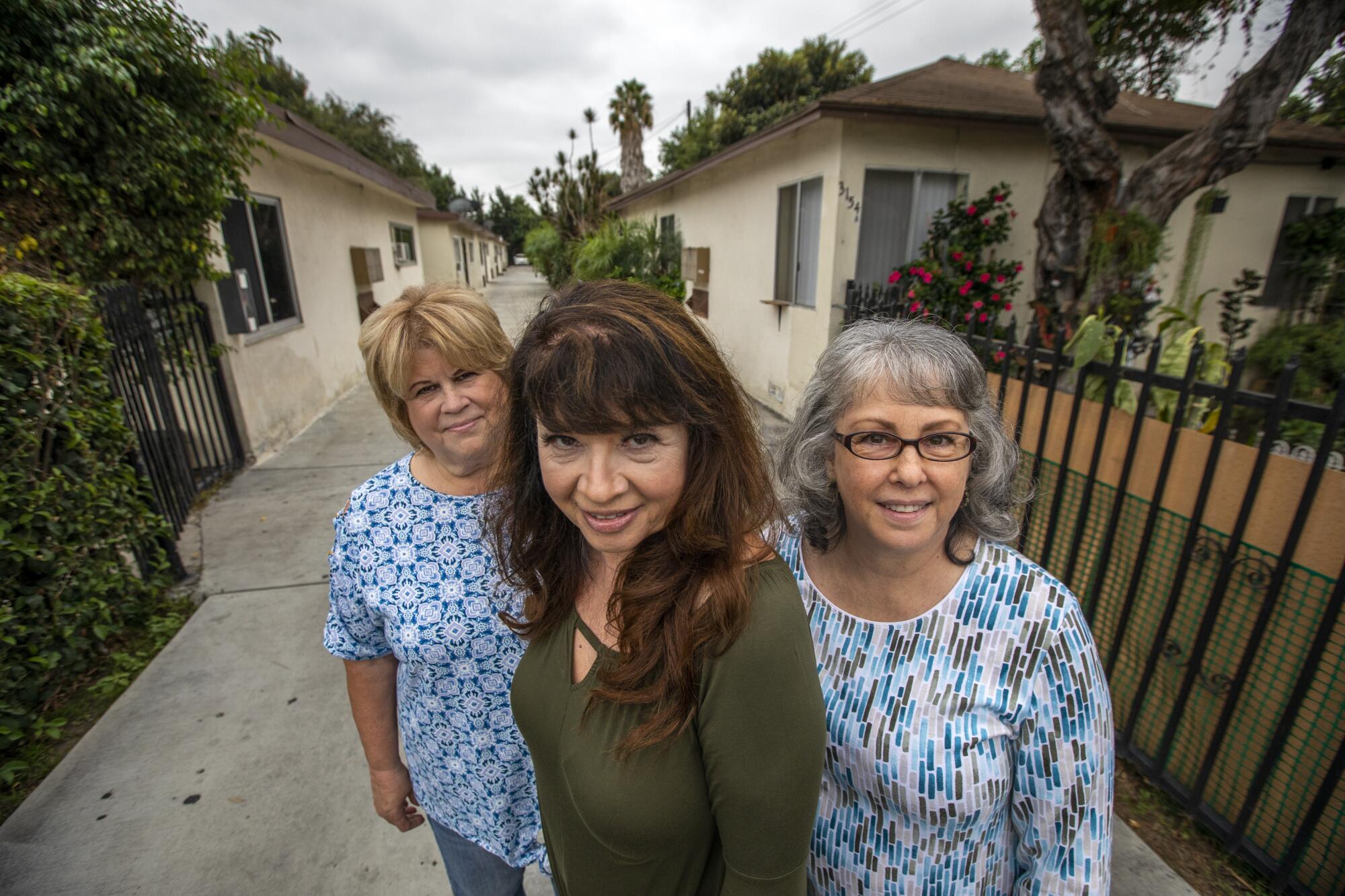 Three women stand together in a residential neighborhood