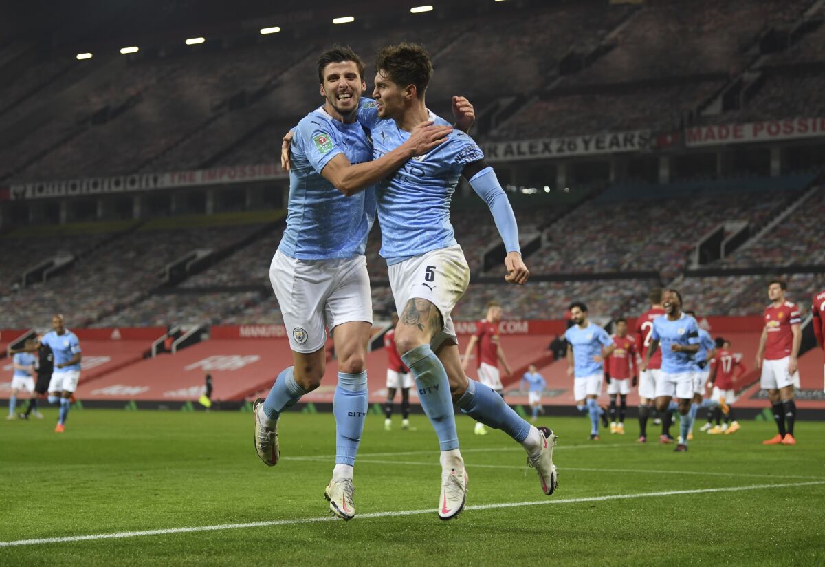 Manchester City's John Stones, right, celebrates after scoring the opening goal of his team during the English League Cup semifinal soccer match between Manchester United and Manchester City at Old Trafford in Manchester, England, Wednesday, Jan. 6, 2021. (Shaun Botterill/Pool via AP)