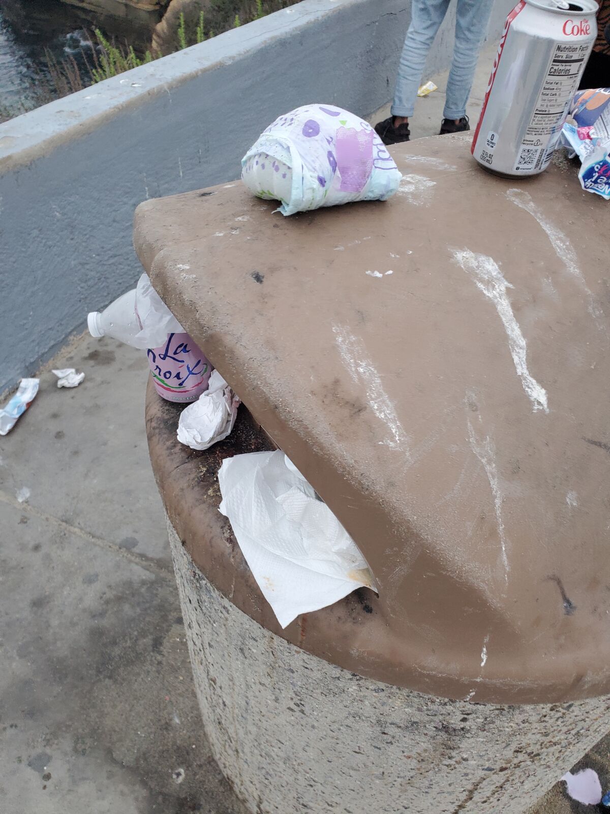 A trash can near the coast overflows with garbage in La Jolla.
