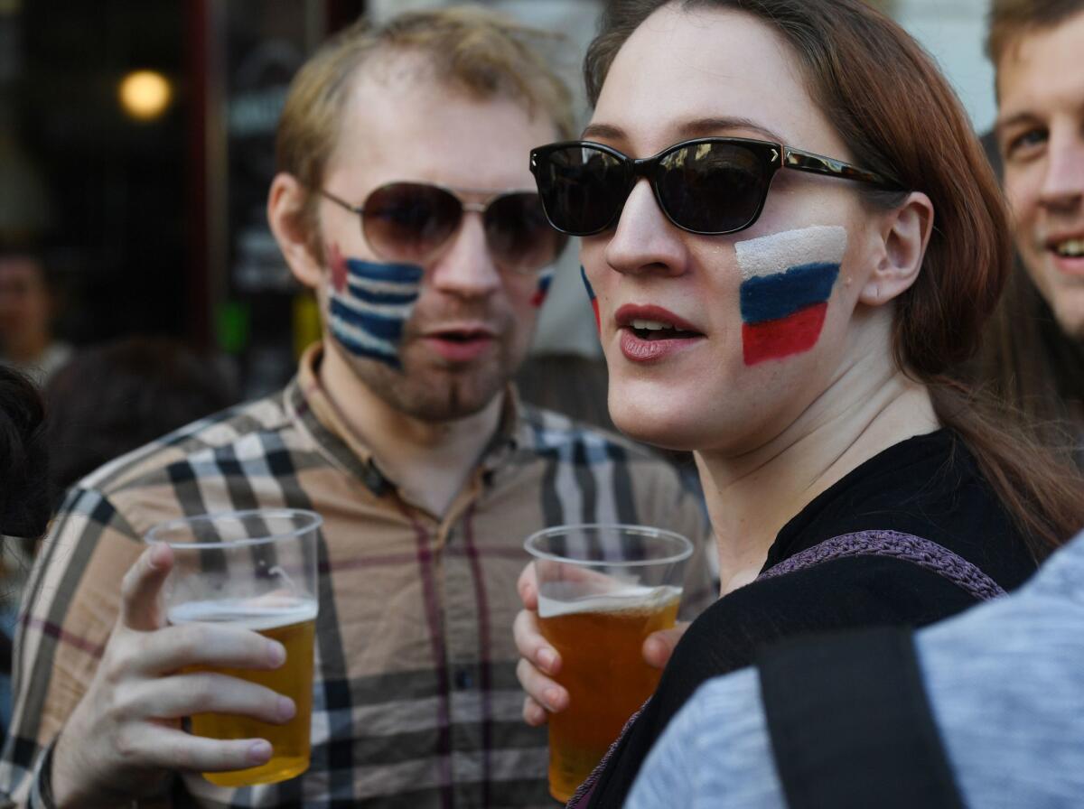 Soccer fans from Uruguay, left, and Russia drink beer in Nikolskaya Street near Red Square in Moscow on June 25, 2018.