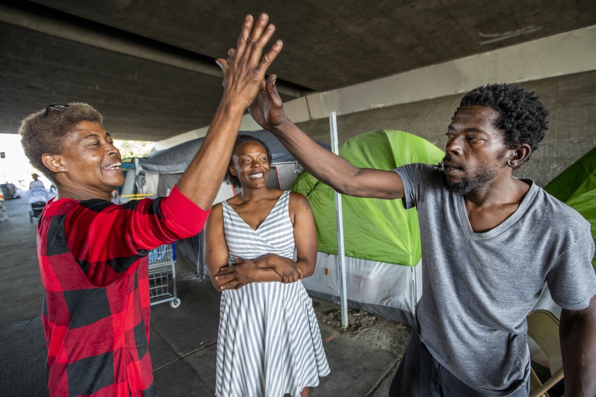 Beatrice Hart, left, gives a high-five to Edwin Williams as Michelle Vaughn watches. Hart recently moved into an apartment in Sunland but returns often to the camp, where she's the unofficial den mother.