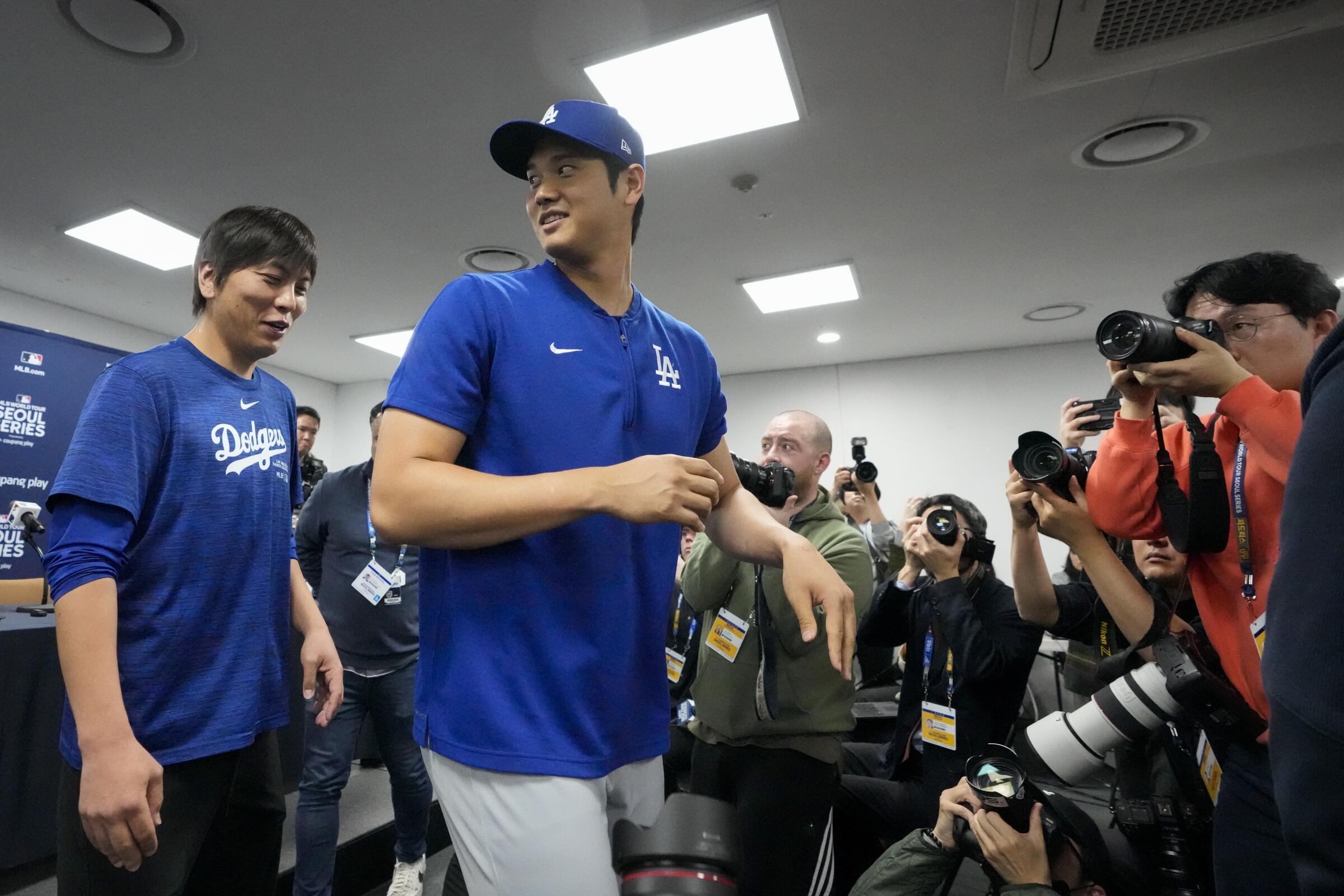 Dodgers star Shohei Ohtani, right, and his interpreter, Ippei Mizuhara, exit after a news conference.