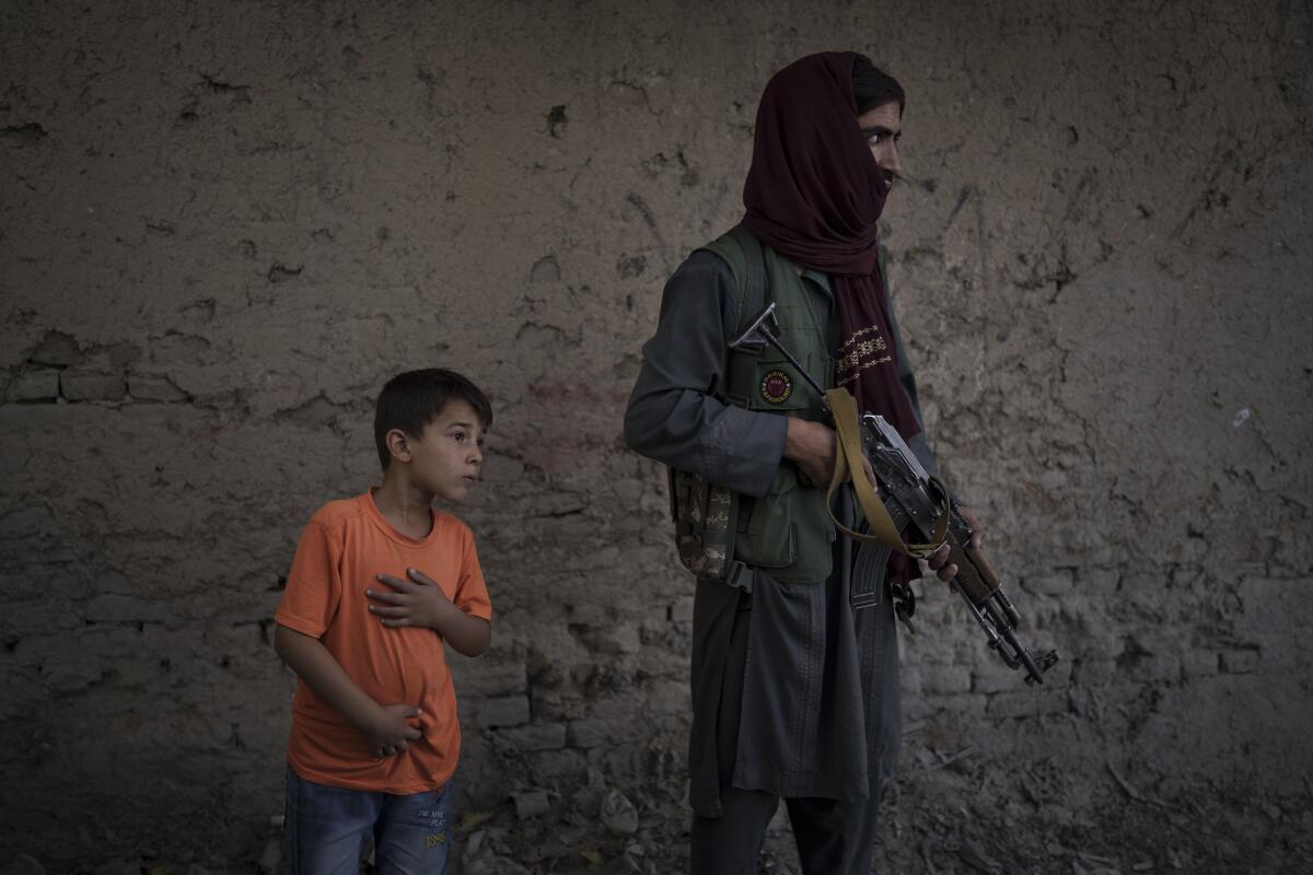 An afghan boy watches as Taliban fighters search for a man accused of stabbing in Kabul, Afghanistan, Sunday, Sept. 12, 2021. The Taliban are shifting from being warriors to an urban police force. (AP Photo/Felipe Dana)