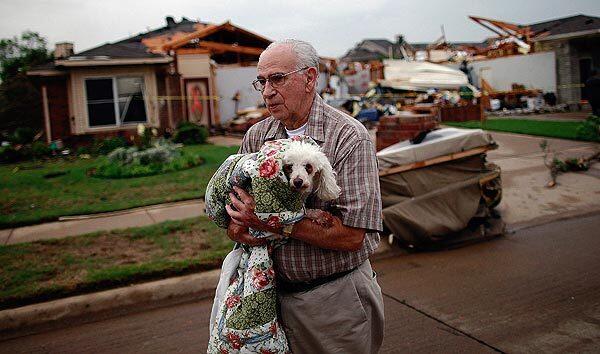 David Lowe carries his daughter's dog, Phoebe, after the canine was rescued from the rubble of a destroyed home in Arlington, Texas. Multiple tornadoes touched down across the Dallas-Fort Worth area, causing extensive damage.