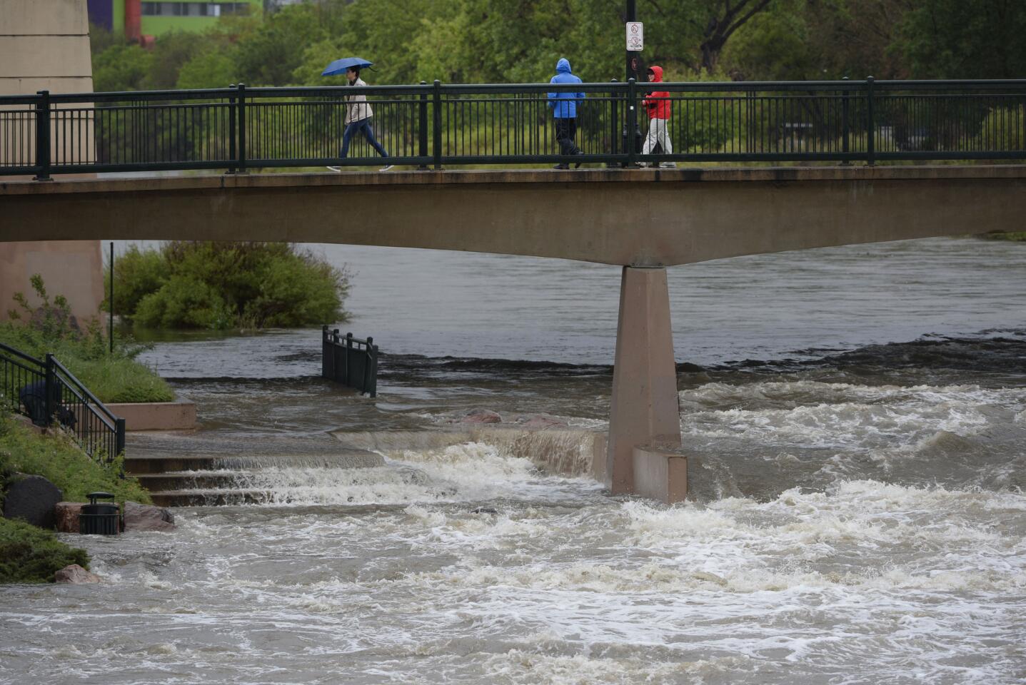 The South Platte spills over onto a walking path underneath the bridge during a heavy rain storm at Confluence Park in Denver.