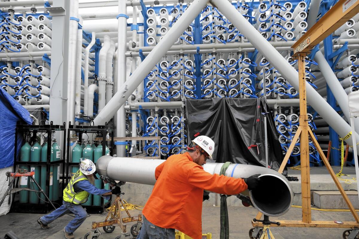 Workers move a pipe in March at a desalination plant under construction in Carlsbad, Calif.