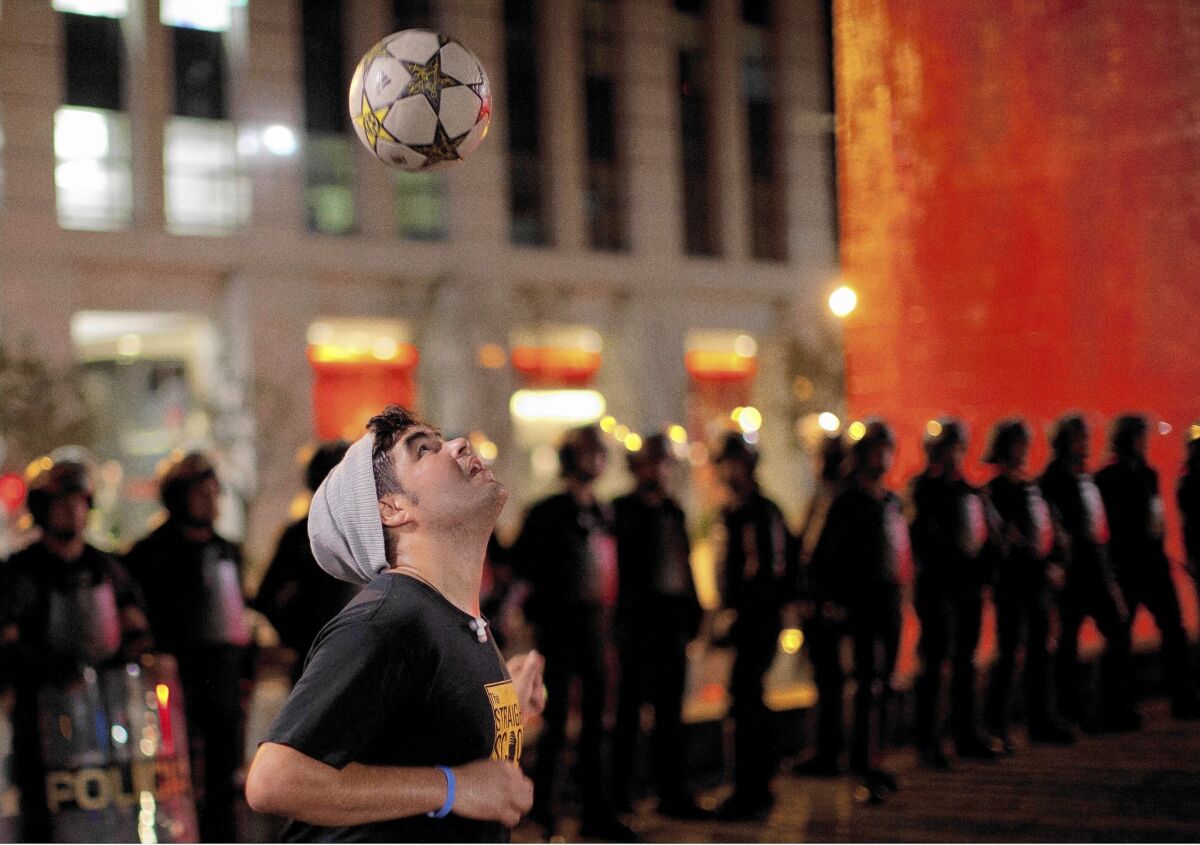 A protester plays with a soccer ball as riot police stand guard in Sao Paulo, Brazil. Hundreds gathered to demand the release of two people arrested during an earlier protest.