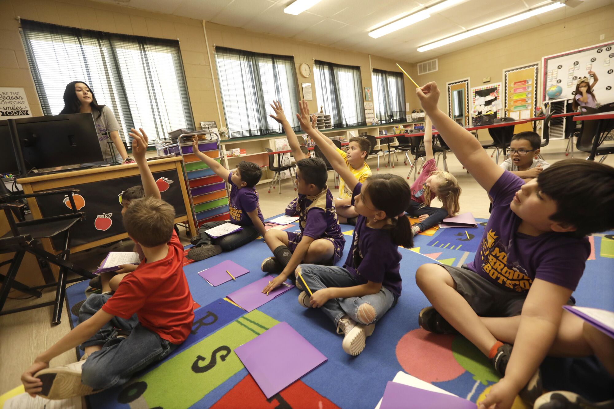 Second grade students raise their hands to answer a question during a math class at Meadow School
