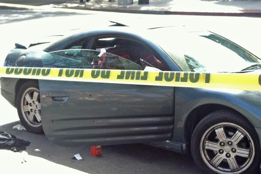 A car with three bullet holes in the door is cordoned off after authorities said it was involved in a car-to-car shooting in South Los Angeles. A man who was wounded in the incident drove to an entrance to USC.