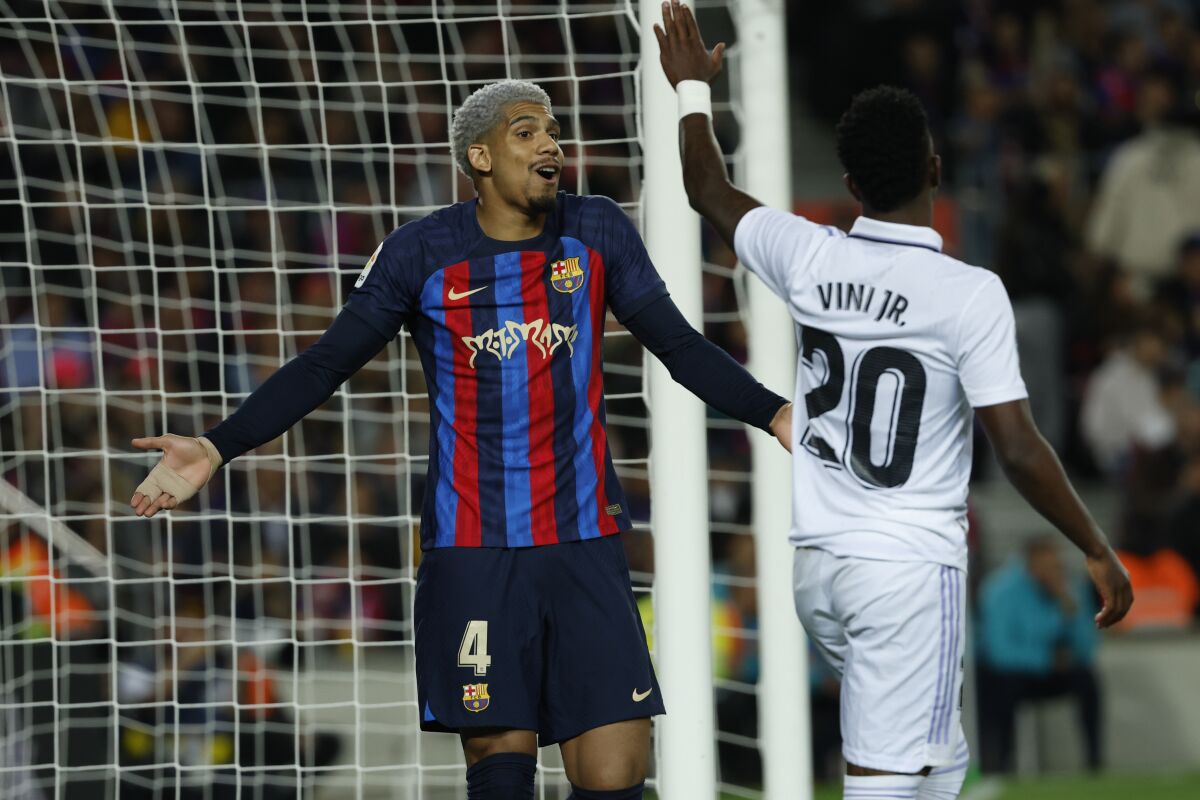Barcelona's Ronald Araujo, left, gestures in front of Real Madrid's Vinicius Junior during Spanish La Liga soccer match between Barcelona and Real Madrid at the Camp Nou stadium in Barcelona, Spain, Sunday, March 19, 2023. (AP Photo/Joan Monfort)